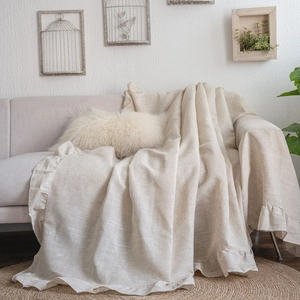 Beige linen sofa throw cover with elegant ruffle edges in a cozy farmhouse home setting