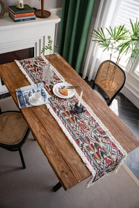Close-up of geometric jacquard table runner with white decorative tassels on wood table