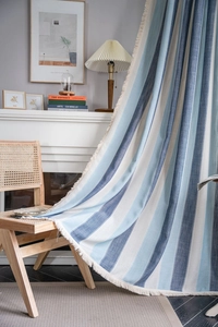 Détail du rideau rayé bleu en coton et lin avec bordure à pompons style rustique