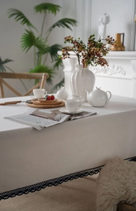 Close-up of white linen tablecloth featuring intricate black lace hollow embroidery edges