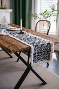 Detailed view of black and white geometric jacquard table runner with decorative tassels