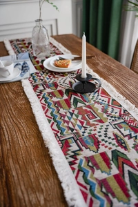 Close-up of geometric jacquard table runner with colorful patterns and white tassels