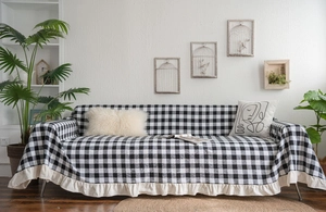Macro detail of black and white checkered sofa cover with ruffled cream-colored lace trim