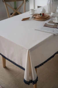 Close-up of white cotton linen tablecloth with elegant navy blue crochet lace edges