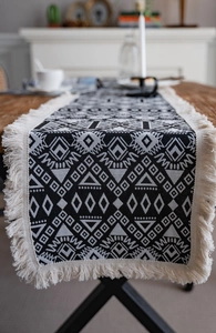 Close-up of black and white geometric jacquard table runner with thick cotton fringe