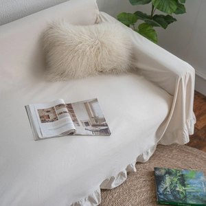 Cream white ruffle sofa cover with elegant frill hem in a minimalist Nordic home setting