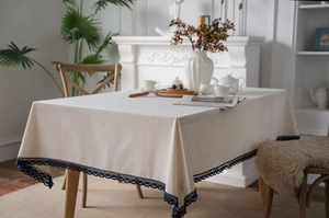 Close-up of beige cotton linen tablecloth with elegant dark blue lace border detailing