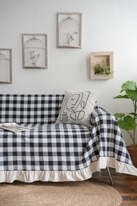 Detail of black and white gingham sofa throw with cream ruffled edges in a modern home setting