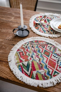 Close-up of bohemian colorful geometric pattern placemat with cream tassels on wood