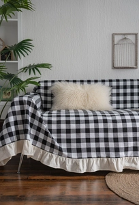 Detail of black and white checkered sofa cover with cream ruffled edge for home decor