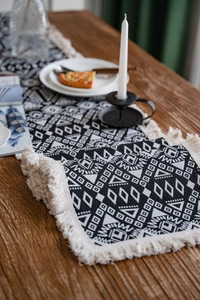 Detailed close-up of monochrome geometric jacquard fabric with thick cotton tassels