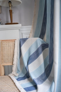 Détail du tissu à rayures bleues avec franges élégantes sur une chaise en osier rétro