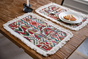 Detailed view of colorful geometric woven table runner with white cotton tassels