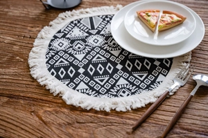 Detailed view of a round black and white geometric table mat with bohemian tassels