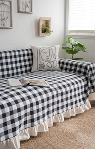 Detail of black and white checkered sofa cover with cream ruffled edges and textured fabric