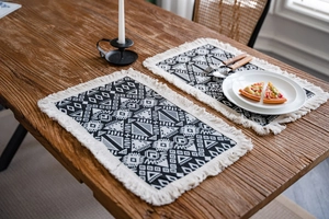 Detail of geometric woven table runner with tassels on a rustic wooden dining table