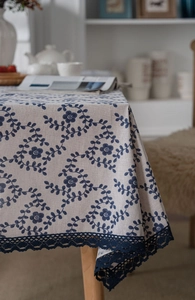 Detailed blue floral linen tablecloth with wide navy crochet lace trim on wooden table