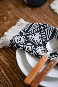 Close-up of black and white geometric jacquard table runner with white cotton fringe detail