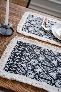 Close-up of black and white geometric table runner with tassels on a rustic wooden table
