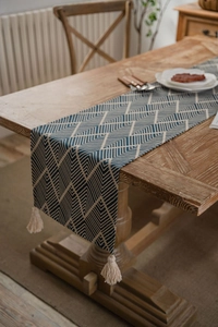 Detailed view of dark blue geometric jacquard table runner with decorative tassels