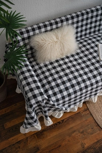 Detail of black and white gingham sofa throw cover with elegant off-white ruffle edges