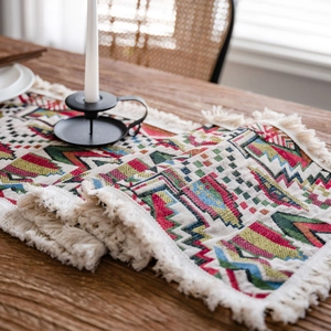 Bohemian geometric woven table runner with tassels on a dark wood dining table