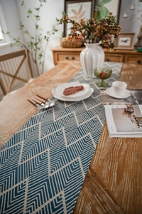Detail view of blue and white geometric jacquard table runner on dark wood table