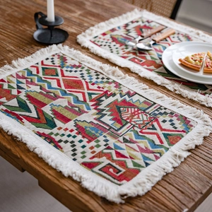 Bohemian geometric woven table runner with white tassels on a rustic dark wood table