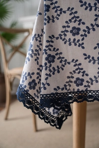 Close-up of dark blue floral print on linen tablecloth with detailed crochet lace border