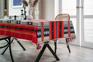 Dettaglio tovaglia stile bohémien con motivi geometrici e rifiniture di nappe crema