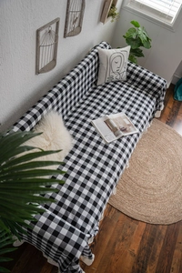 Detail of black and white gingham sofa cover with ruffled edges in a warm home setting