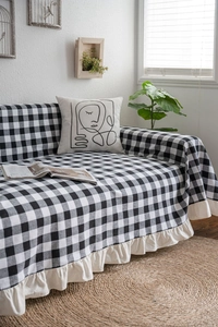 Detail of black and white gingham sofa throw with ruffle trim edges and textured fabric
