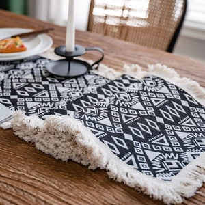 Modern black and white geometric table runner with cotton tassels on a wooden dining table