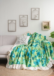 Detail of multi-color floral sofa throw with decorative cream ruffle edge and soft fabric