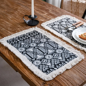 Bohemian black and white geometric table runner with tassels on a rustic wooden table