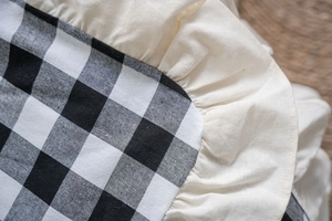 Detail of black and white gingham fabric with decorative cream ruffled edge trimming
