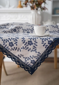 Close-up of vintage floral tablecloth with blue vine prints and delicate lace edge