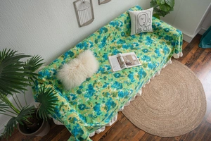 Close-up of green floral sofa cover with ruffled hem and decorative bohemian style