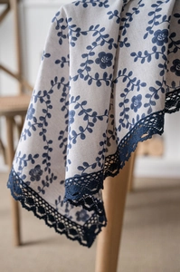 Detail view of cotton linen tablecloth featuring navy floral prints and lace edges