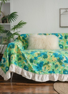 Detail of green floral sofa cover with romantic white ruffled edge and soft fabric texture
