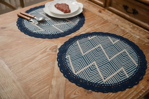 Macro detail of round placemat with blue geometric pattern and crochet lace trim