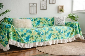 Close-up of green floral sofa cover featuring elegant white ruffle edge and linen texture