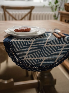 Close-up of geometric jacquard table runner with delicate blue lace edging on wood table