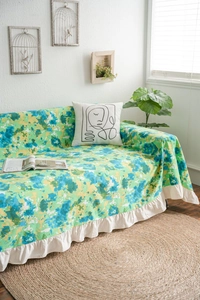 Close-up of floral sofa cover with blue-green camo print and white ruffle edge detail