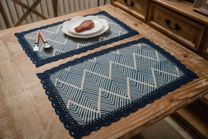 Detail of blue geometric placemat with navy crochet lace on wooden dining table