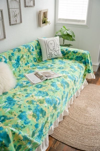 Detail of blue and green abstract ink sofa cover with elegant white ruffle skirt hem