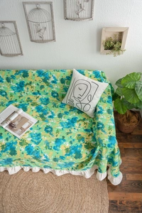 Detail of floral sofa cover featuring green abstract print and white ruffled edges