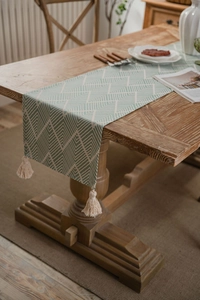 Detail of Nordic jacquard geometric table runner with handmade fringe on dark wood table