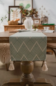 Close-up of green geometric jacquard table runner with decorative cotton tassels