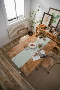 Detail of mint green geometric table runner with white fringe and herringbone pattern